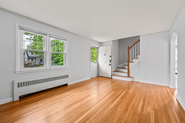 foyer featuring stairs, baseboards, radiator, and light wood-type flooring