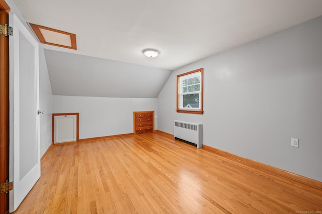 bonus room with baseboards, radiator heating unit, lofted ceiling, and light wood-type flooring