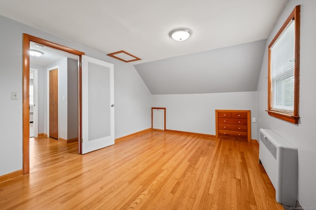 bonus room featuring baseboards, vaulted ceiling, radiator heating unit, and light wood-type flooring