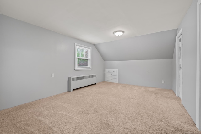 additional living space featuring carpet floors, radiator, and vaulted ceiling