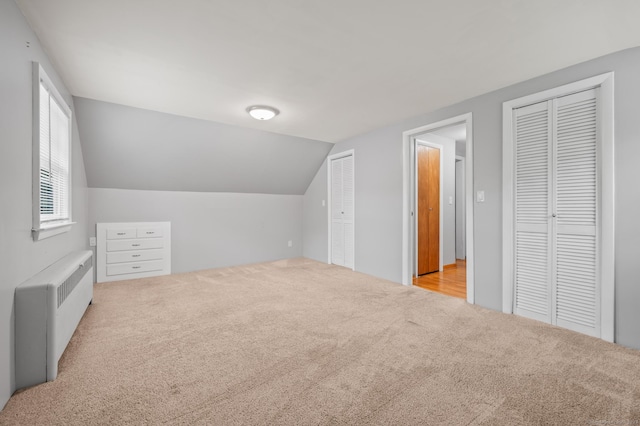 additional living space with carpet floors, radiator heating unit, and lofted ceiling