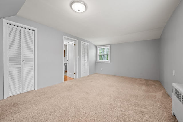 unfurnished bedroom featuring ensuite bathroom, carpet, and radiator heating unit