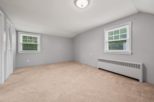 additional living space featuring a healthy amount of sunlight, radiator, carpet floors, and lofted ceiling