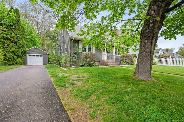 view of front of home with a garage, aphalt driveway, fence, a front yard, and an outbuilding