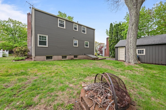 back of house featuring a lawn, an outdoor structure, and a chimney