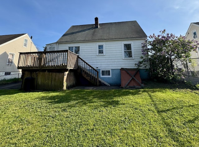 rear view of house featuring a chimney, a lawn, a deck, stairway, and fence
