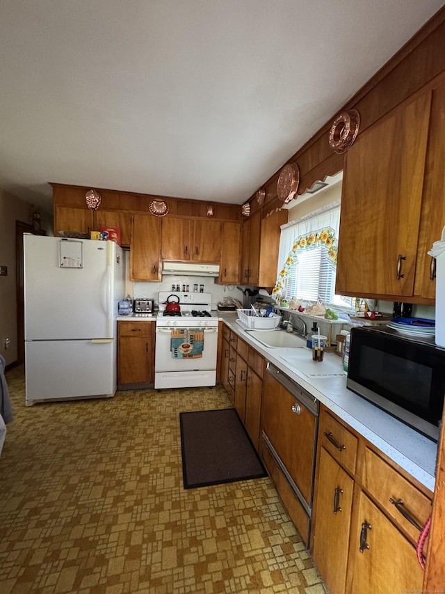 kitchen featuring white appliances, light countertops, under cabinet range hood, brown cabinets, and a sink