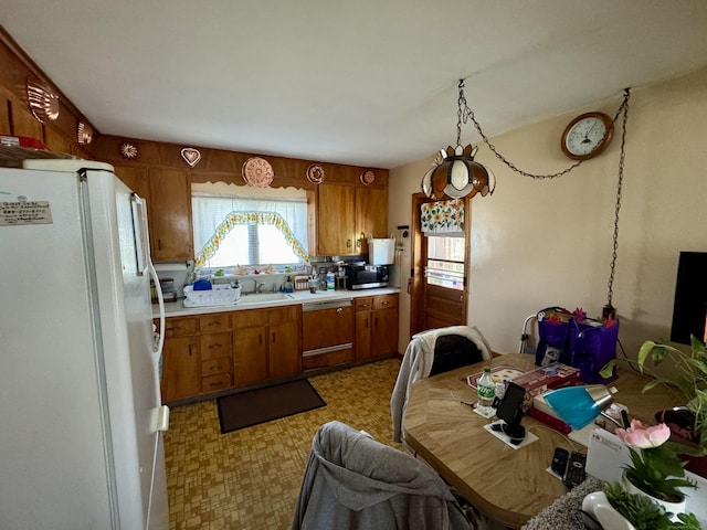 kitchen with dishwasher, brown cabinetry, freestanding refrigerator, stainless steel microwave, and light floors