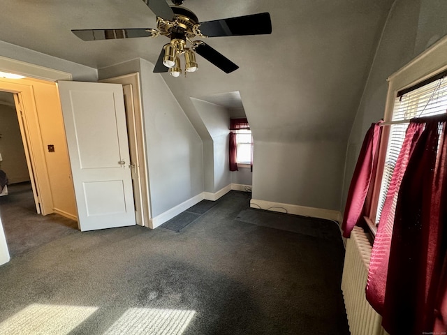 bonus room with a ceiling fan, baseboards, dark carpet, and radiator