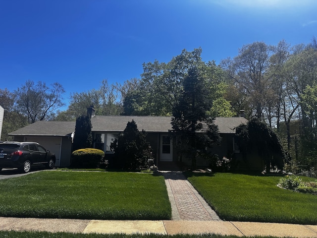 ranch-style home with a garage, a chimney, and a front yard