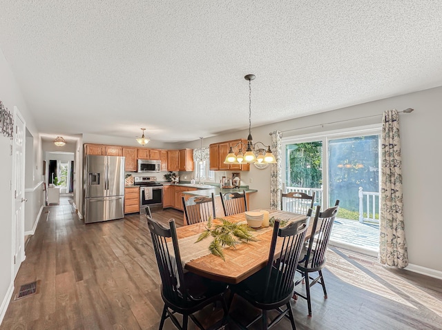 dining room with a chandelier, a textured ceiling, visible vents, and dark wood-style floors