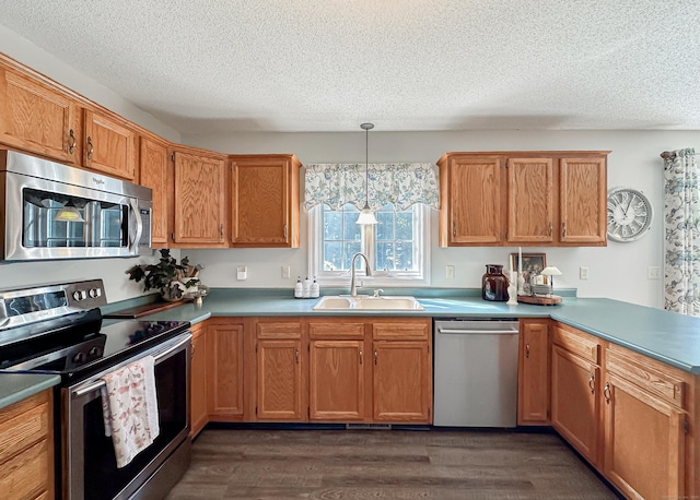 kitchen with a sink, a textured ceiling, appliances with stainless steel finishes, and a peninsula