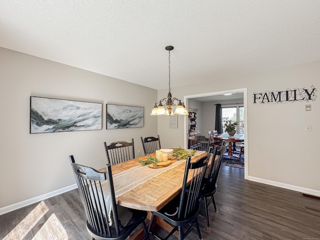 dining room with dark wood-style flooring, a notable chandelier, a textured ceiling, baseboards, and visible vents