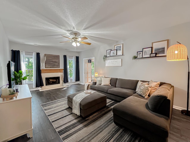 living room featuring a premium fireplace, a ceiling fan, a wealth of natural light, and dark wood-style flooring