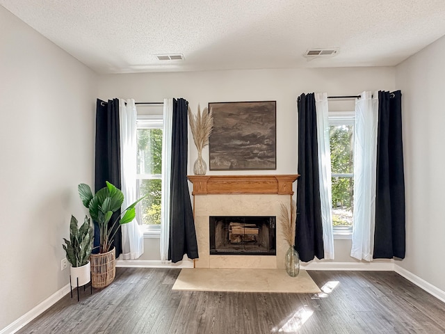 living area featuring visible vents, a high end fireplace, a textured ceiling, and wood finished floors