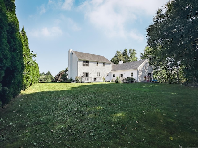 rear view of house with a lawn, a chimney, and a deck