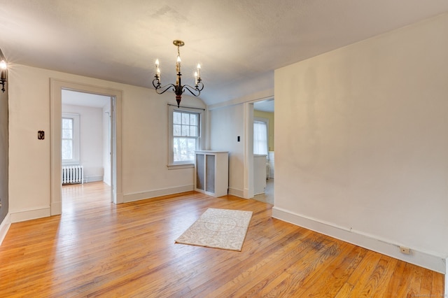 interior space with baseboards, an inviting chandelier, a healthy amount of sunlight, and radiator heating unit