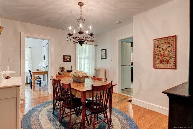2951 Winsted Rd, Torrington, CT 06790 - dining space featuring radiator heating unit, a chandelier, light wood-style floors, and baseboards