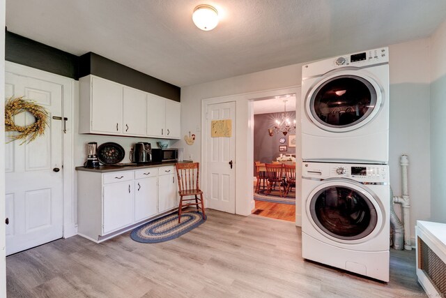 2951 Winsted Rd, Torrington, CT 06790 - laundry area with stacked washing machine and dryer, light wood finished floors, and a chandelier
