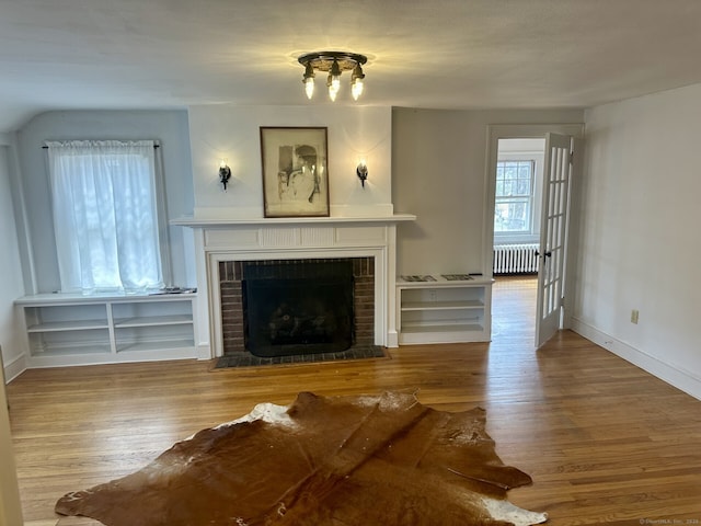 2951 Winsted Rd, Torrington, CT 06790 - living area featuring radiator, wood finished floors, and a brick fireplace
