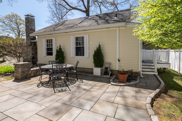 2 Bartholomew Rd, Branford, CT 06405 - back of property featuring roof with shingles, a patio area, outdoor dining area, and a chimney