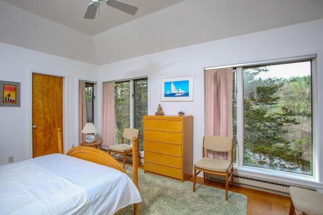 bedroom with a baseboard radiator, ceiling fan, light wood-type flooring, and multiple windows
