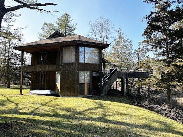 exterior space featuring stairway, a wooden deck, a shingled roof, and a yard