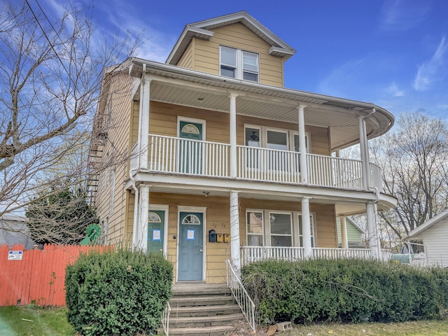 view of front facade featuring a porch, fence, and a balcony