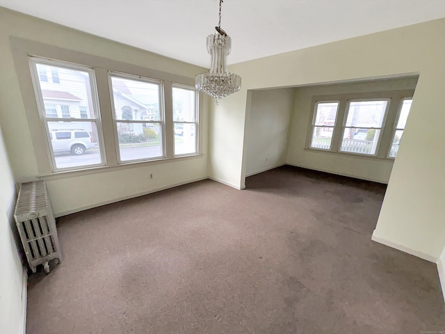 carpeted spare room with baseboards, a notable chandelier, and radiator