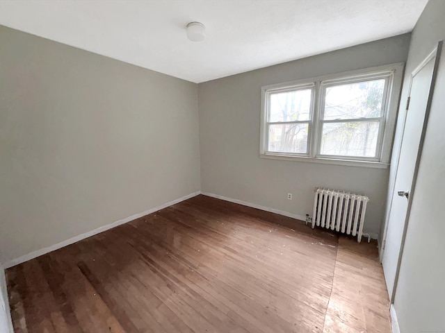 unfurnished bedroom featuring light wood-style floors, baseboards, and radiator heating unit