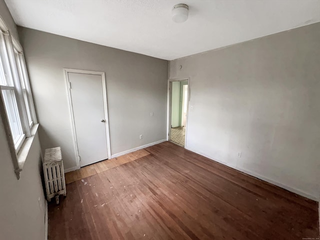 interior space featuring radiator heating unit, baseboards, and wood-type flooring