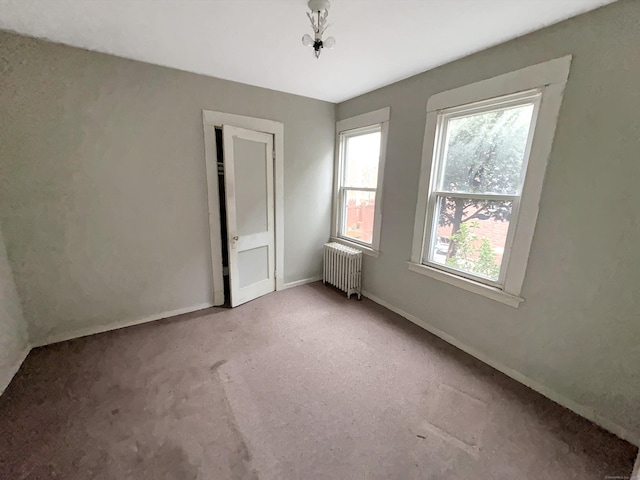 unfurnished room with radiator, baseboards, and carpet
