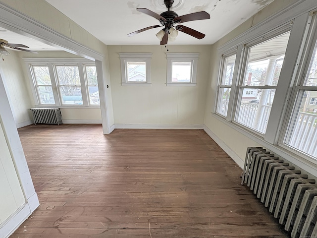 unfurnished sunroom with wood-type flooring, a wealth of natural light, and radiator heating unit