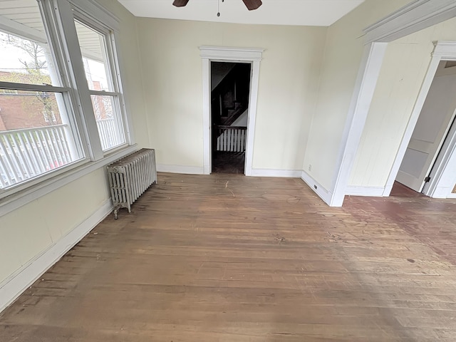 spare room featuring a ceiling fan, hardwood / wood-style flooring, baseboards, and radiator