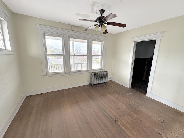 spare room with ceiling fan, a wealth of natural light, radiator heating unit, and wood finished floors
