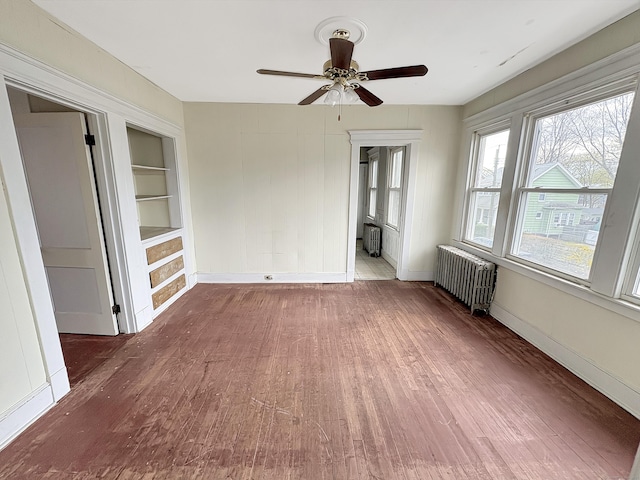 unfurnished bedroom featuring baseboards, ceiling fan, wood finished floors, and radiator