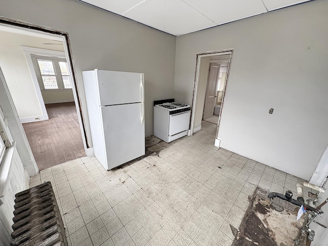 kitchen featuring baseboards and white appliances