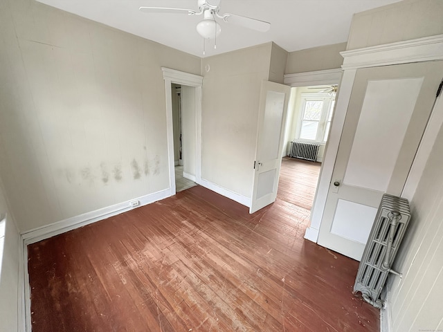 unfurnished bedroom with wood-type flooring, baseboards, ceiling fan, and radiator heating unit