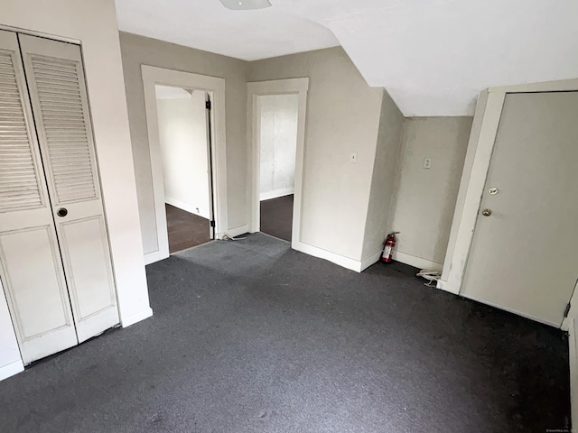 interior space featuring baseboards and dark carpet