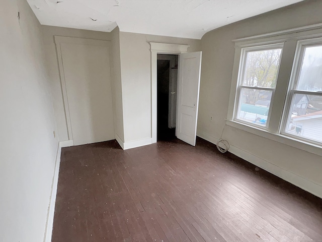 unfurnished bedroom with baseboards and dark wood finished floors