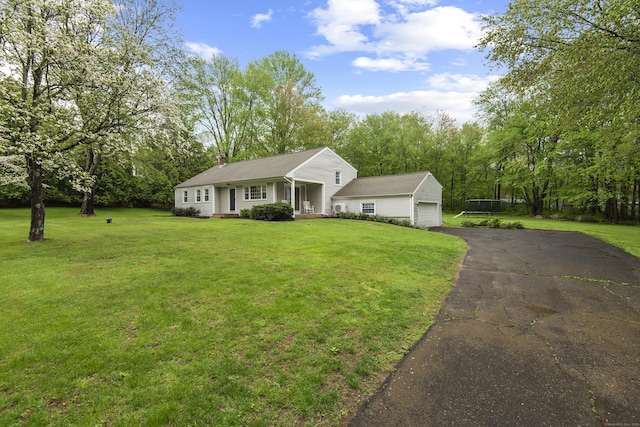 view of front of home featuring a front lawn, asphalt driveway, and view of wooded area