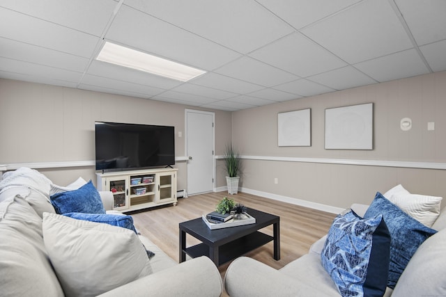 living room featuring a drop ceiling, wood finished floors, and a baseboard radiator