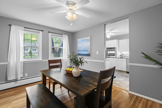 dining area with a ceiling fan, light wood-type flooring, and a baseboard heating unit