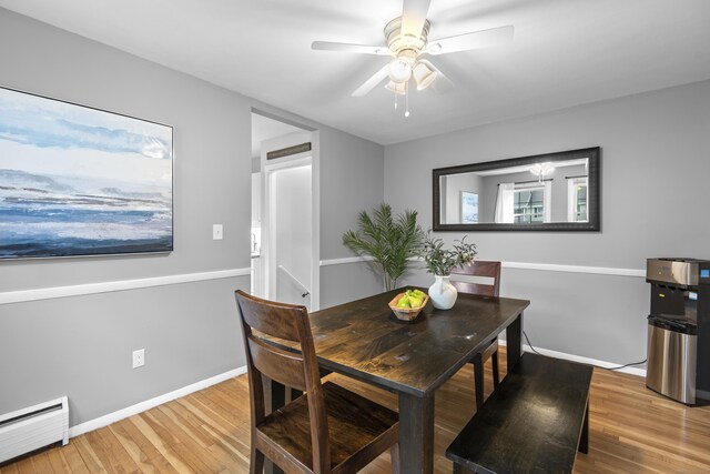 dining space with a baseboard radiator, wood finished floors, ceiling fan, and baseboards
