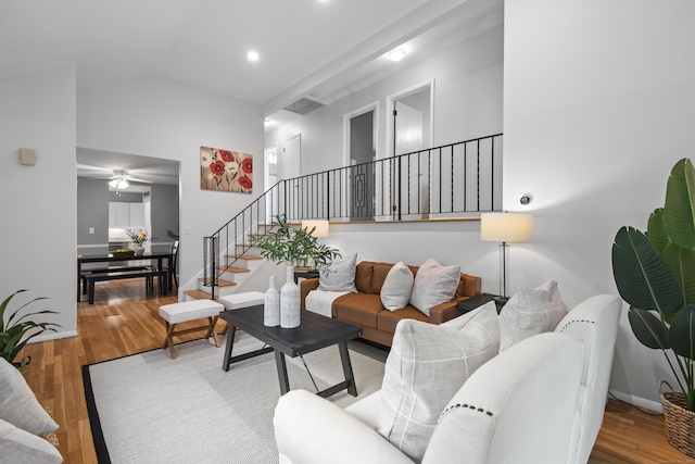 living room featuring stairway, wood finished floors, a ceiling fan, vaulted ceiling, and baseboards