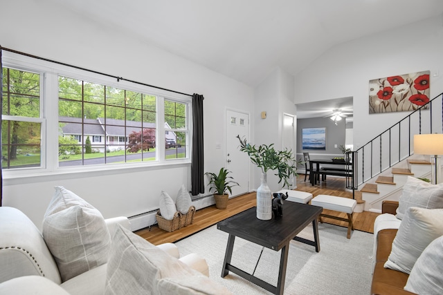 living area with stairway, wood finished floors, lofted ceiling, baseboard heating, and ceiling fan