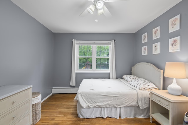 bedroom with baseboard heating, wood finished floors, ceiling fan, and baseboards