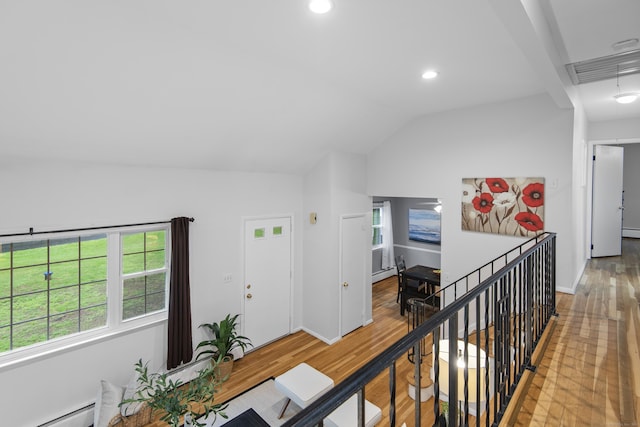 hallway with recessed lighting, wood finished floors, baseboard heating, plenty of natural light, and vaulted ceiling