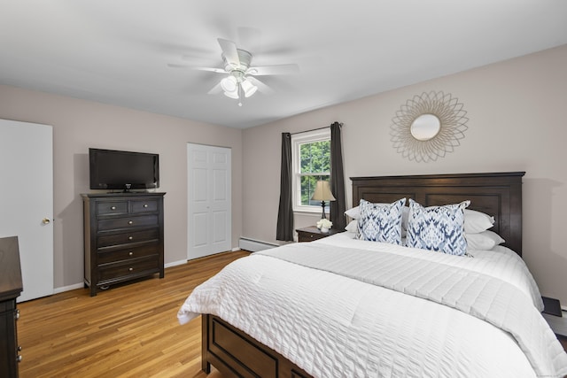 bedroom with a baseboard heating unit, light wood-style flooring, baseboards, and a ceiling fan