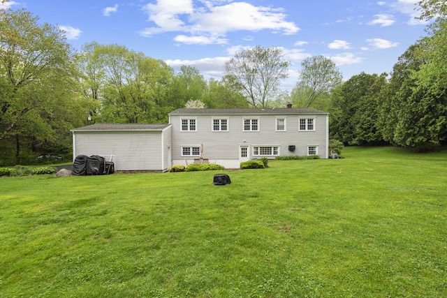 rear view of house with a lawn, a chimney, and view of wooded area